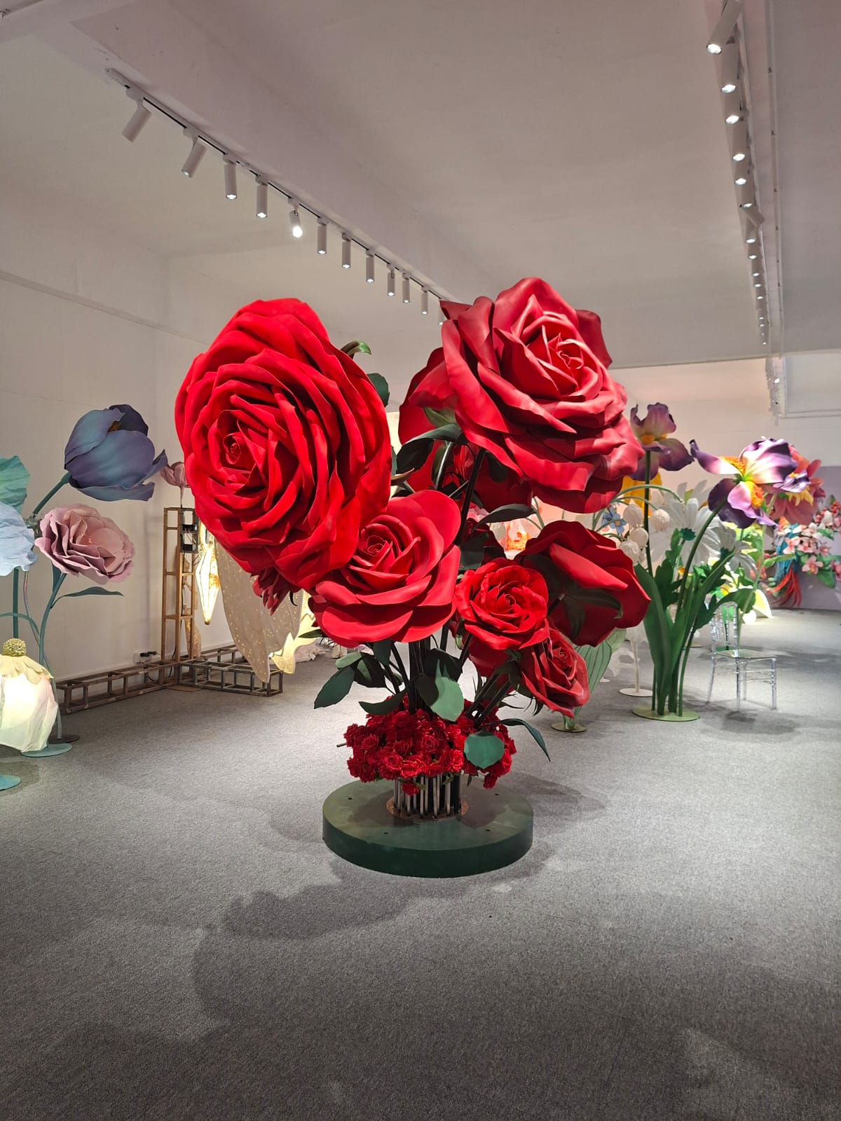 A monumental bouquet of oversized red roses on a green pedestal in the Sparking Joy studio